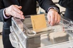 Personne déposant son bulletin de vote dans une urne
